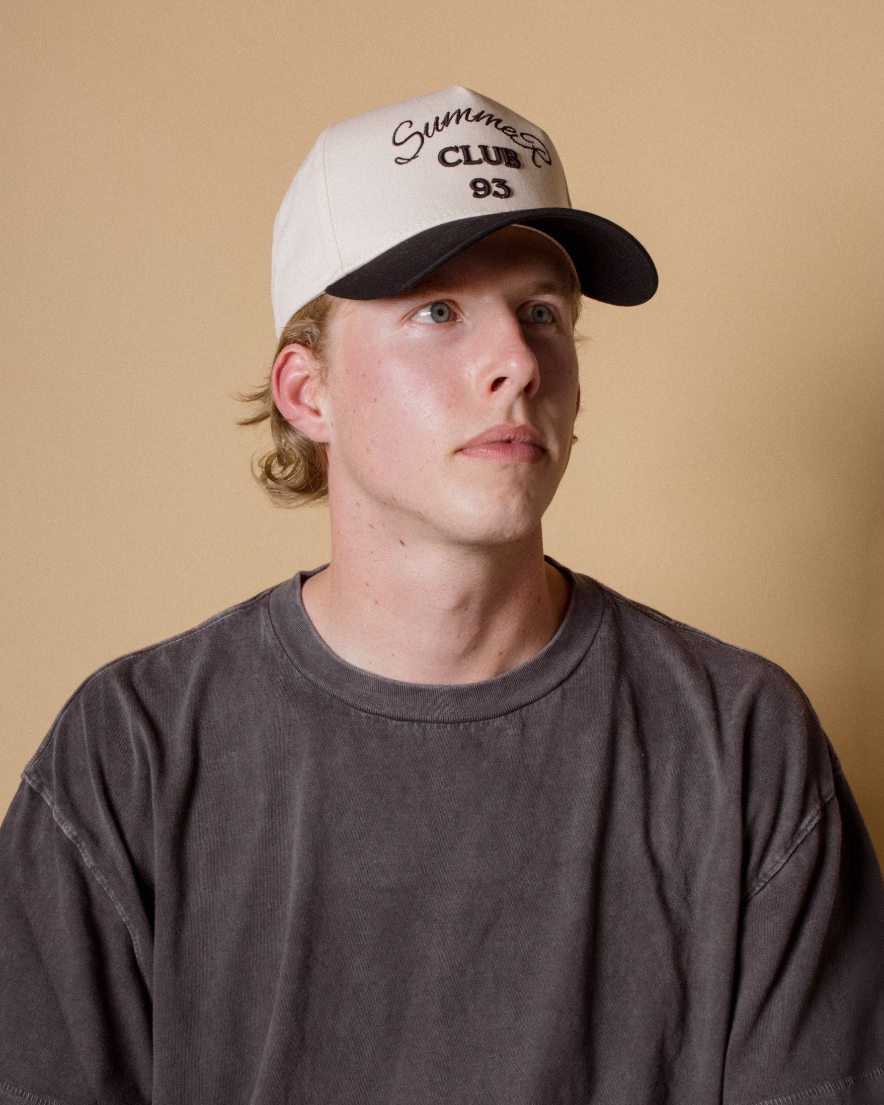 Man wearing a cap with text on a beige background